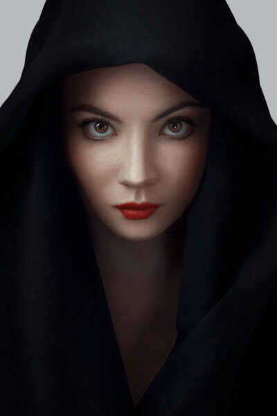 Woman wearing scarf with hood. Beautiful woman big eyes covers her face with a black cloth. Red lips girl under hood. isolated on gray background
