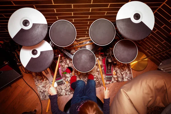 Kleine kaukasische Schlagzeugerin, die das elektronische Schlagzeug spielt. Mädchen lernt Schlagzeug in der Musikschule. Emotionales Porträt — Stockfoto