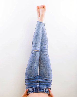 Women's jeans legs demonstration without shoes, studio shooting on gray background closeup clipart