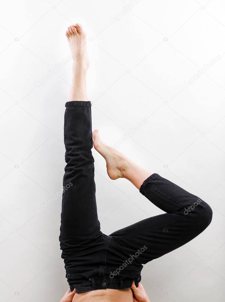 Women's jeans legs demonstration without shoes, studio shooting on gray background closeup