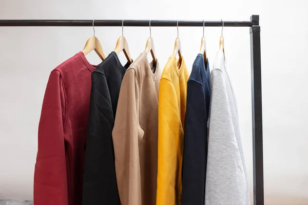 Camisolas em branco penduradas em um cabide no guarda-roupa ou showroom — Fotografia de Stock
