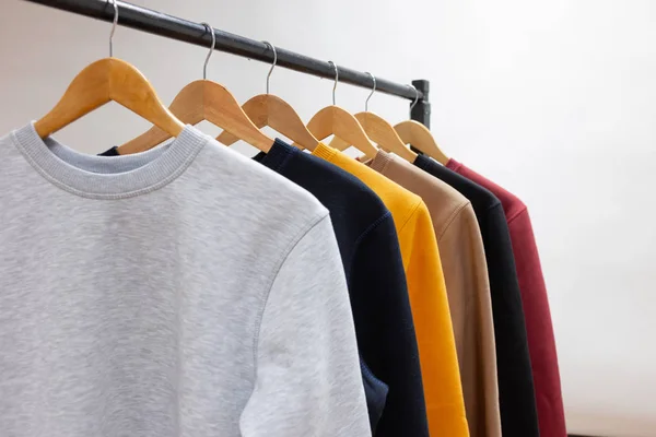 Blank sweatshirts hanging on a hanger in the wardrobe or showroom — Stock Photo, Image