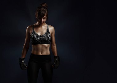 Fotokopi alanı ile spor dövüş konsepti. Siyah boks eldivenli, gri spor sutyen ve siyah üzerine poz veren kadın portresi.