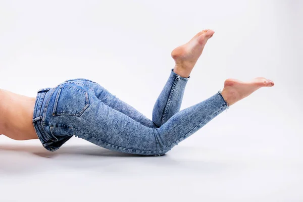 Gri Arka Planda Çıplak Ayaklı Kot Pantolonlu Güzel Bir Kadının — Stok fotoğraf