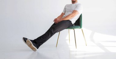 Evde boş tişörtlü bir adam var. Düşünceli bir bakışla pencerenin yanındaki sandalyede oturmak. Yazdırma için model