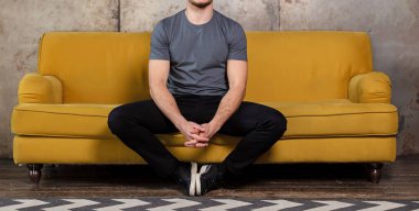 Yakışıklı, rahat bir genç adam evinde kanepede oturuyor. Senin için boş gömlekli bir adam.