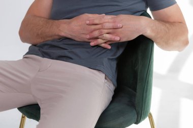 Evde boş tişörtlü bir adam var. Düşünceli bir bakışla pencerenin yanındaki sandalyede oturmak. Yazdırma için model