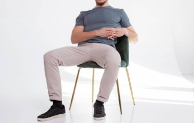 Evde boş tişörtlü bir adam var. Düşünceli bir bakışla pencerenin yanındaki sandalyede oturmak. Yazdırma için model