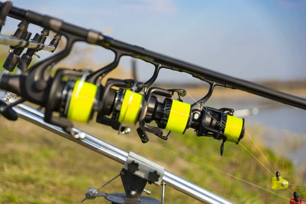 Close up view of multiple carp fishing reel coil on rods on rod pod near lake river. Fishing during sunset — Stock Photo, Image