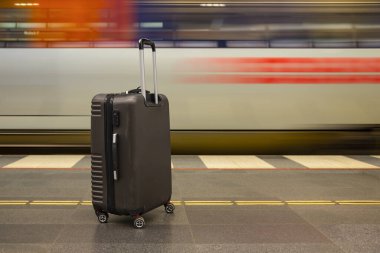 Hareket halindeki trenin yanındaki tren istasyonunda bagajlar tekerleklerin üzerinde. Seyahat sırasında istasyonda beklemek ya da valizlerle tatil yapmak