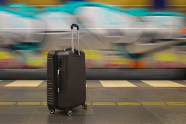 Hareket halindeki trenin yanındaki tren istasyonunda tekerlek üstünde duran bagajlar. Seyahat sırasında beklemek ya da bavulla tatil.