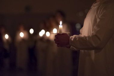 Erkekler kilisedeki geleneksel dini kıyafetlerle mumları tutuyorlar. İsveç 'te Lucia Günü kutlaması