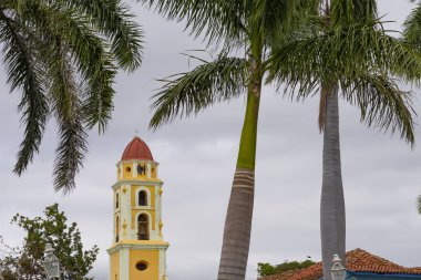 Küba, Trinidad 'daki palmiye ağaçları arasında tarihi yapı kulesi. Kış boyunca bulutlu gri gökyüzünün altındaki eski kule