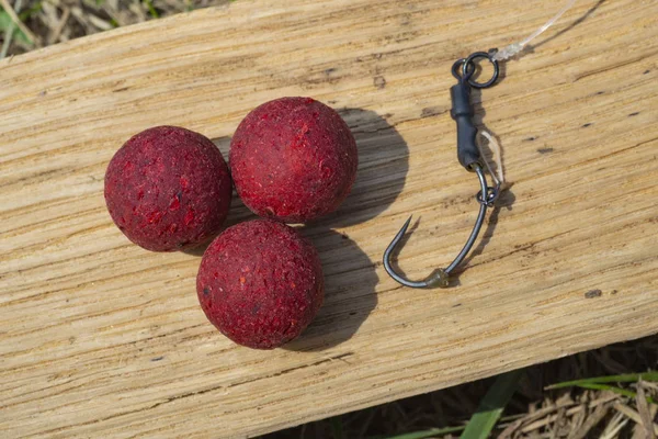 Robin Red Boilies with fishing hook. Fishing rig for carps, boilie rig, near the lake on a piece of wood — Stock Photo, Image