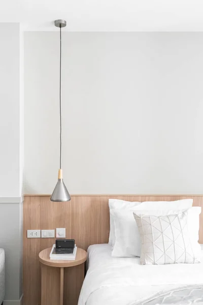 Hjørne av soverom med rustfri smykkelampe og sidebord av tre i moderne skandinavisk stil / moderne modell med minimalt / koselig interiør – stockfoto