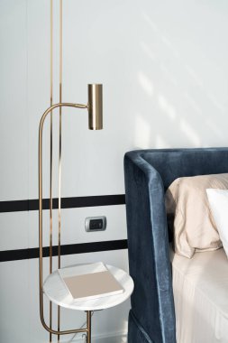 Yatak odası köşesi lacivert kadife yatak dairesel mermer komodinlerle dekore edilmiş yumuşak yastıklar ve arka planda lacivert boya duvarı / rahat iç tasarım