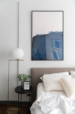 Konforlu yatak odası köşesi modern kahverengi kumaştan yatak başlığı ve altın lambalı rahat yastıklar ve yan masadaki cam vazoda yapay bitki / iç tasarım dekorasyonu / kopyalama alanı