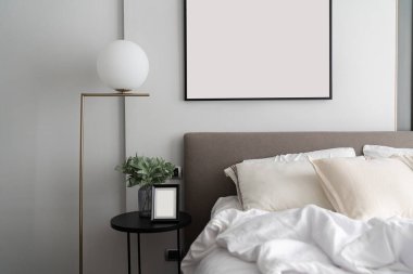 Konforlu yatak odası köşesi modern kahverengi kumaştan yatak başlığı ve altın lambalı rahat yastıklar ve yan masadaki cam vazoda yapay bitki / iç tasarım dekorasyonu / kopyalama alanı