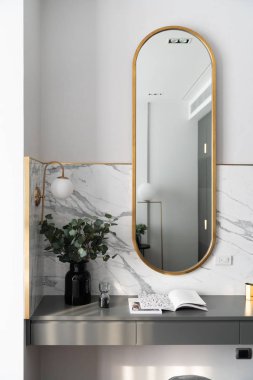 Yatak odası çalışma odası köşesi altın paslanmaz ayna ve gri sprey boyalı çalışma masasında cam vazoda yapay bitki mermer duvar arka planı / apartman içi / telif alanı ile dekore edilmiş.