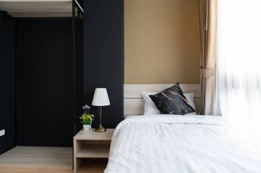 Ahşap yatak başlıklı şık yatak odası köşesi ve yumuşak yastıklı yatak arka planda lacivert ve sarı boyalı duvar / rahat iç tasarım / modern iç tasarım