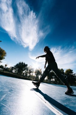 Genç çocuk dans ediyor ve basketbol sahasında poz veriyor.