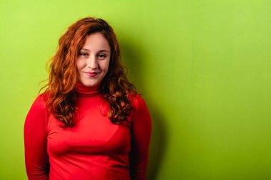 Kırmızı tişörtlü ve yeşil arkaplanlı güzel bir kızıl kız. Metin için alanı kopyala