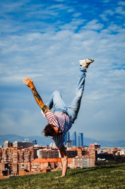 B-boy bazı hareketleri sergiliyor. Modern şehir arka planında break dansçı