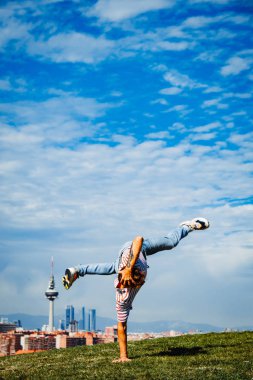 B-boy bazı hareketleri sergiliyor. Modern şehir arka planında break dansçı