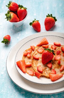 Mavi ahşap arka planda taze çilekli krepler.