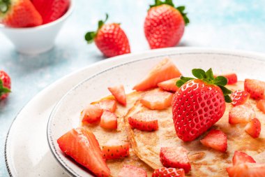 Mavi ahşap arka planda taze çilekli krepler.