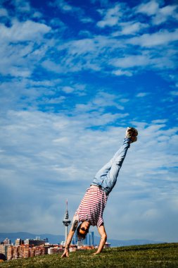 B-boy bazı hareketleri sergiliyor. Modern şehir arka planında break dansçı