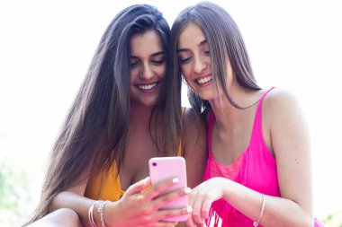 Mayolu iki kız cep telefonlarını kullanıyor ve havuzda eğleniyorlar. Kapat.