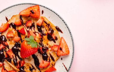 Mavi ahşap arka planda taze çilekli krepler.