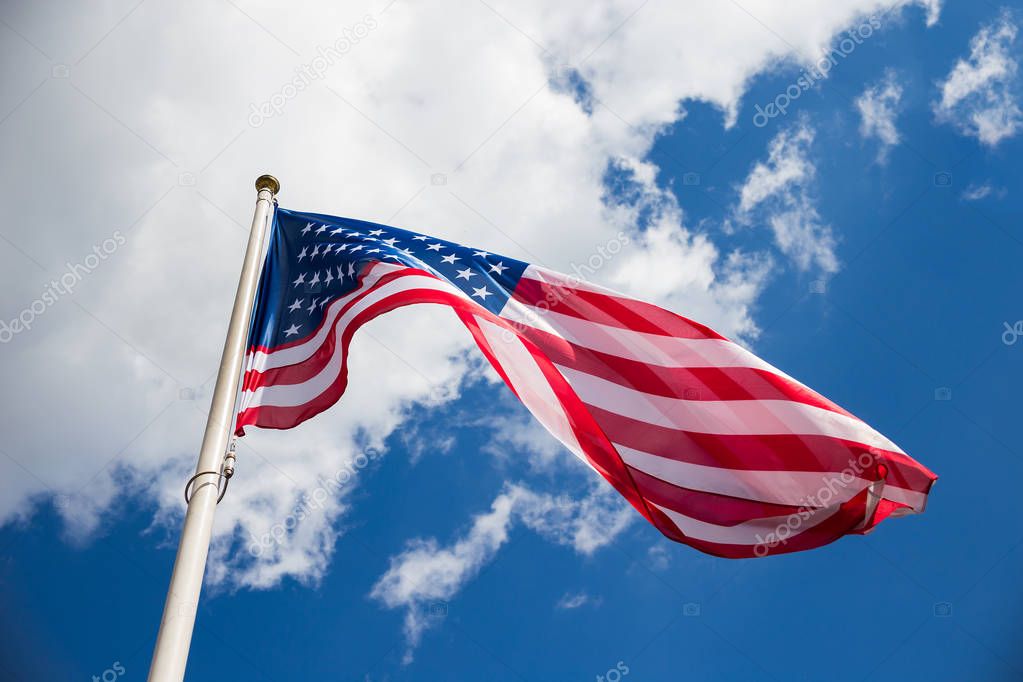 American flag against a blue sky with clouds