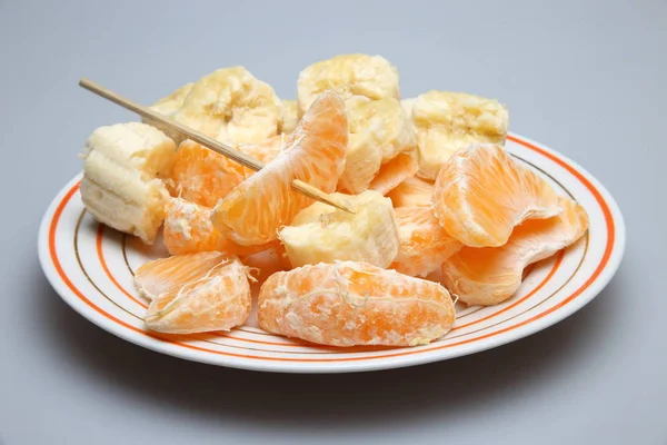 Кусочки апельсинов и бананов на тарелке . — стоковое фото