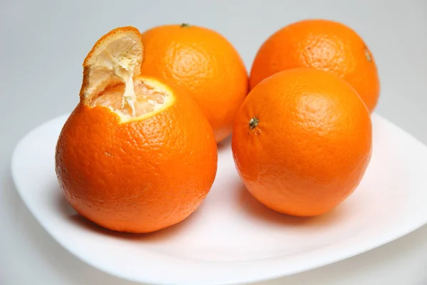 Algumas tangerinas na placa no fundo claro . — Fotografia de Stock