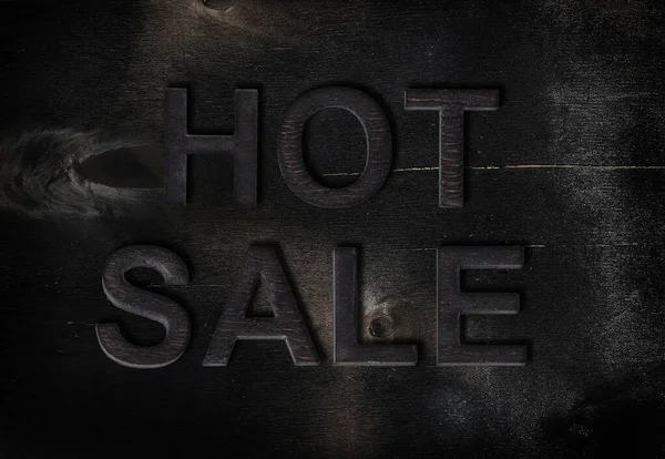 Inscription Hot Sale of charred letters  on wood background