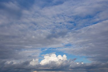 Gökyüzünde beyaz desenli bulutlar, yaz mevsiminin doğal arka planına zıt.