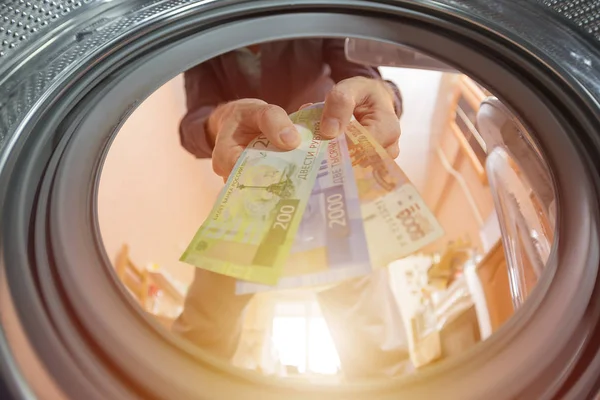 a man throws money rubles into a washing machine, the concept of illegal entrepreneurship, money laundering, and breaking the law and tax evasion