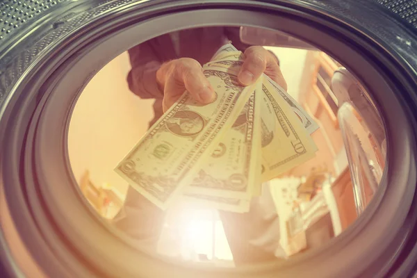 a man throws money dollars into a washing machine, the concept of illegal entrepreneurship, money laundering, and breaking the law and tax evasion