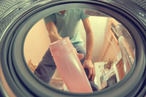 人把洗涤剂或粉末倒入洗衣机 从洗衣机的内部看 — 图库照片