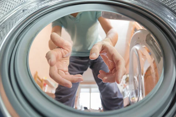 A man or woman throws dirty Laundry in the wash, look from the inside of the washing machine