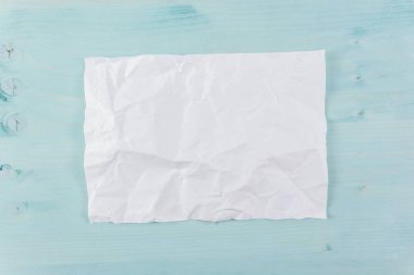 Cyan ahşap arka planda buruşmuş bir kağıt parçası.