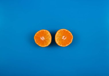 Renkli arka planda dilimlenmiş mandalina, mavi renkte portakal meyvesi