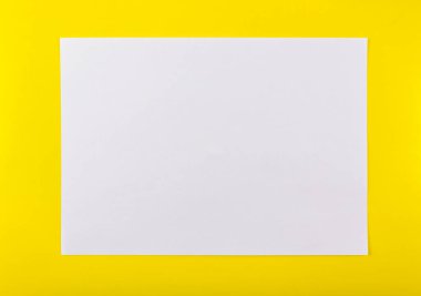 Saf sarı arkaplan üzerine beyaz ofis kağıdı.