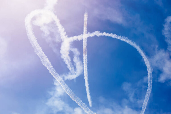 Перевернутый след облаков от самолета к голубому небу в форме сердца, признание в любви

