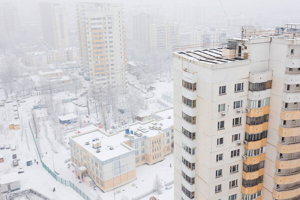 Top view of residential buildings, city during snowfall, white roofs of houses