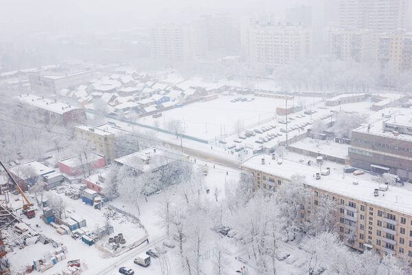 Top view of residential buildings, city during snowfall, white roofs of houses