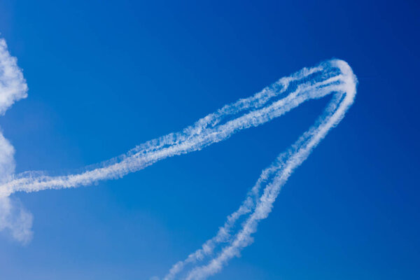 Inversion trail of clouds from the plane against the blue sky