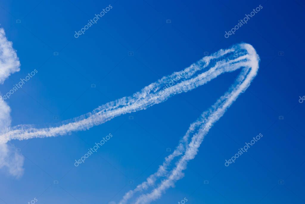 Inversion trail of clouds from the plane against the blue sky